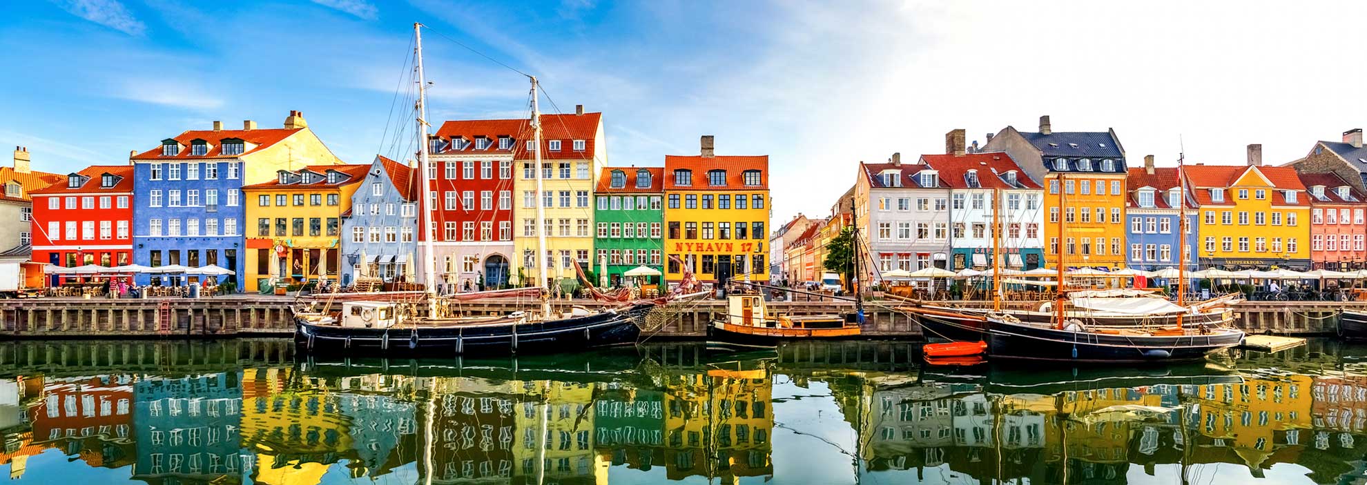 Nyhavn in Kopenhagen mit bunten Häusern und Schiffen im Hafen.